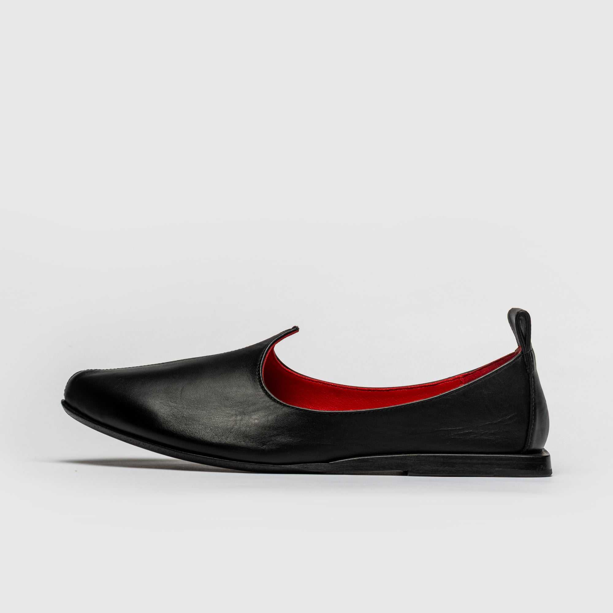 Black shoe with red lining on a white background