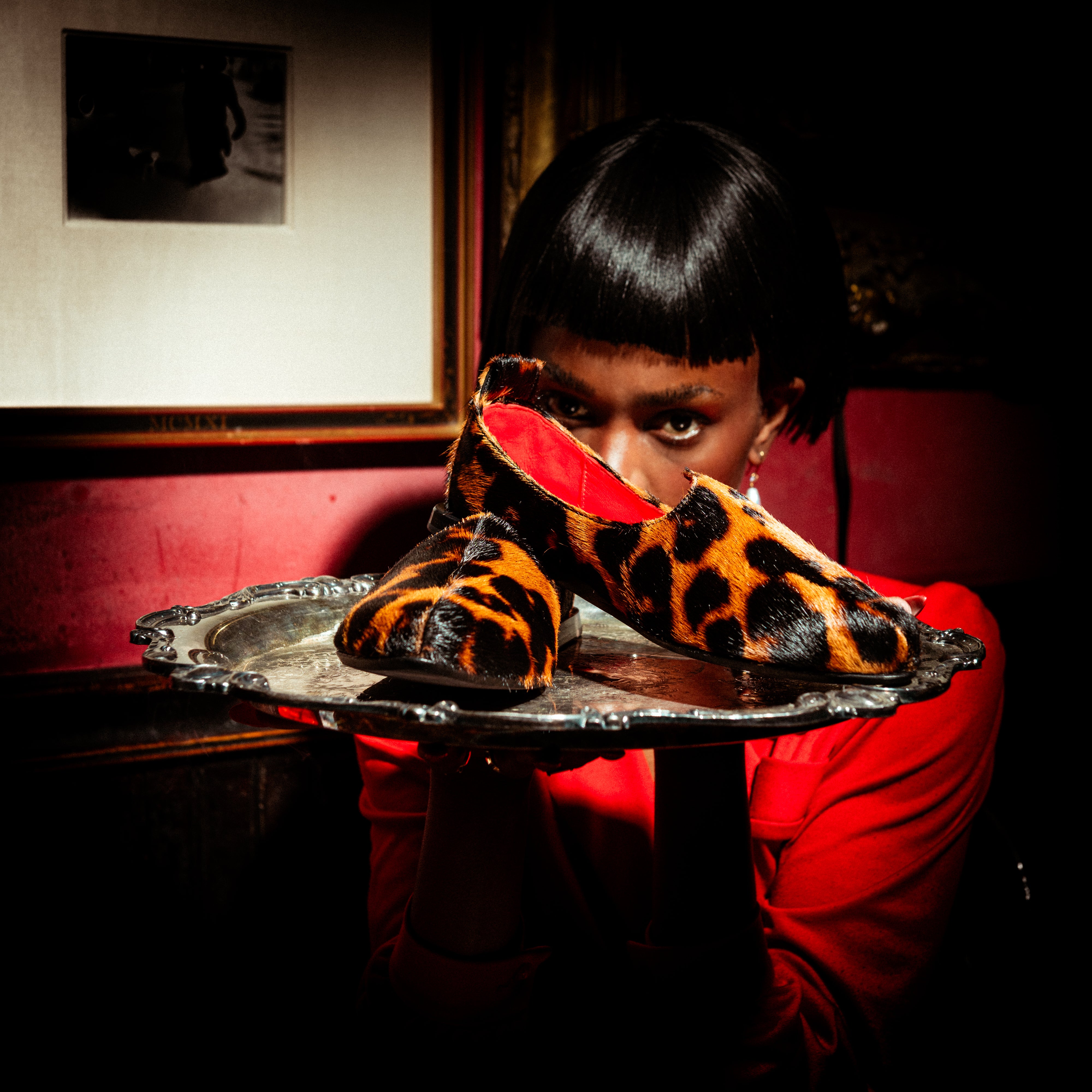 People in a dimly lit bar with red walls and framed pictures on the wall. Wearing JOCO Royal Mojri, Men women in a party scene at Justine's Austin. Creative Photoshoot for luxury loafers for men and women. Handmade in Italy with Luxury Italian leathers. 