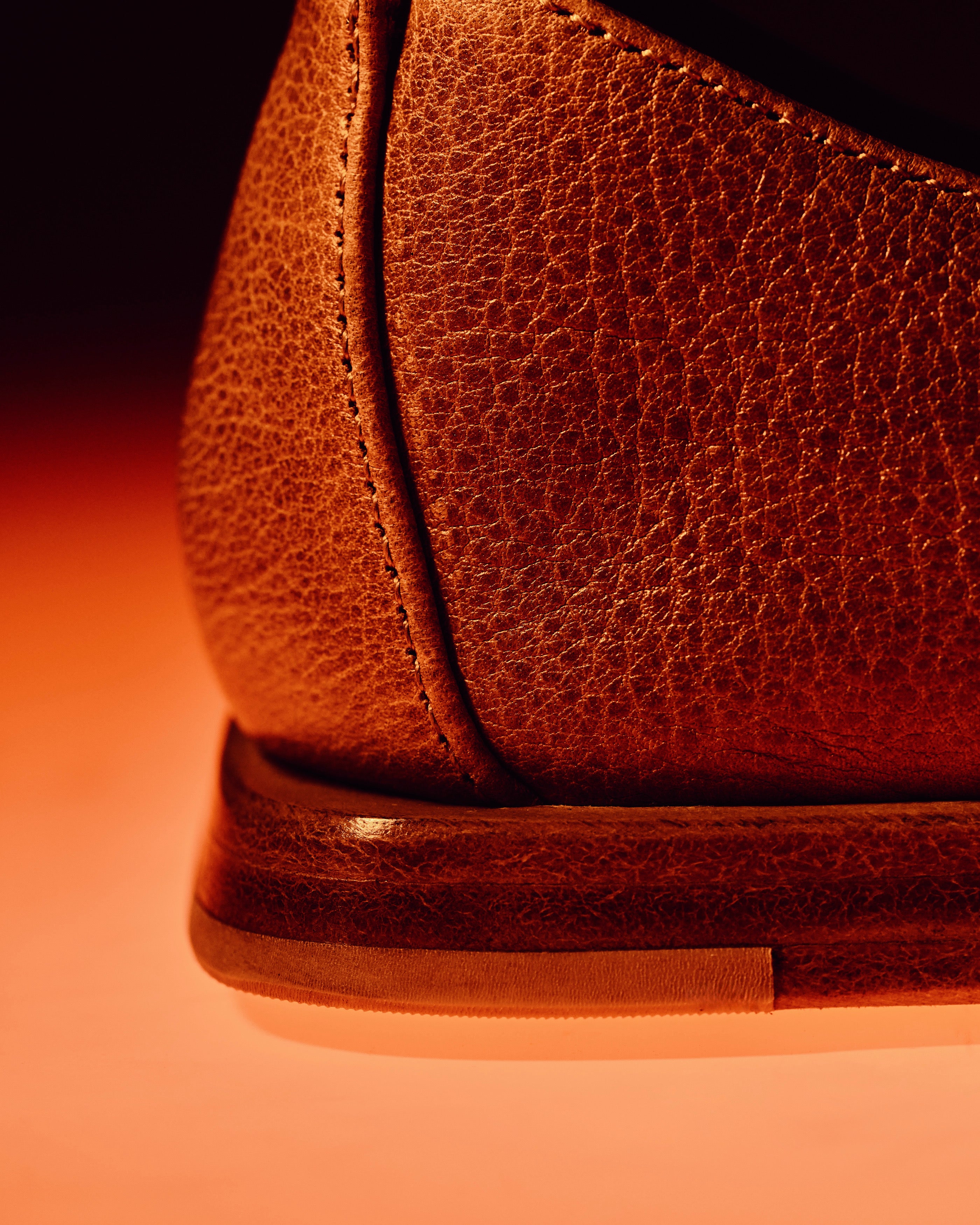 Close-up of a brown leather mojri made in italy product with a warm color gradient.
