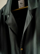 Slim-fit emerald green 10 Paisa Shirt with notch lapel, custom coin buttons, and short sleeves made from organic cotton satin