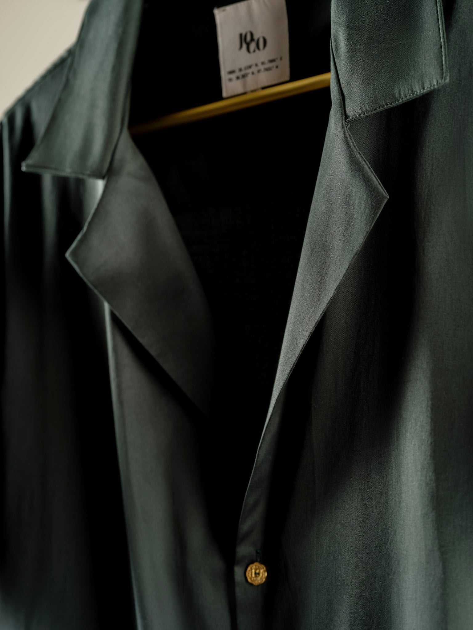 Slim-fit emerald green 10 Paisa Shirt with notch lapel, custom coin buttons, and short sleeves made from organic cotton satin